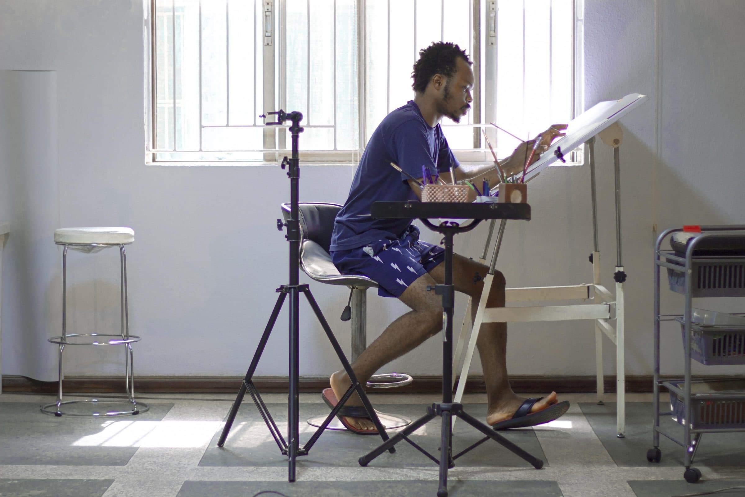 Fatola drawing at an easel in a bright studio