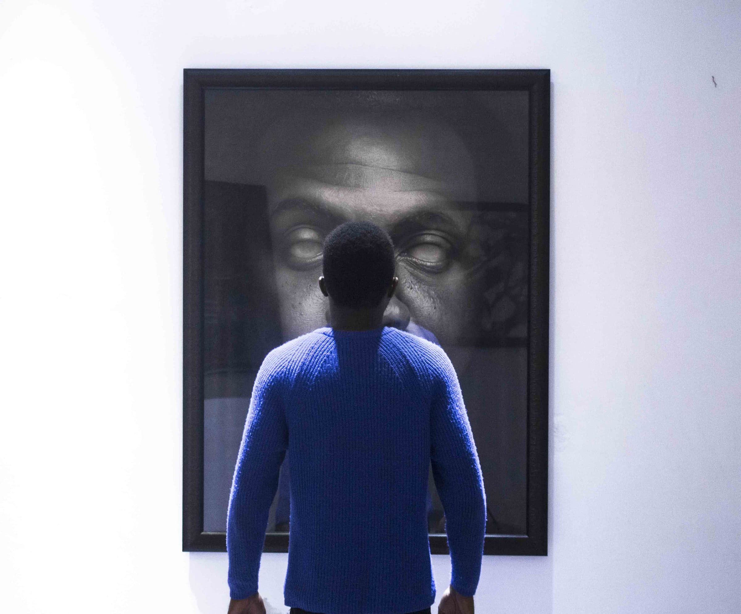 Fatola standing in front of a large framed charcoal portrait