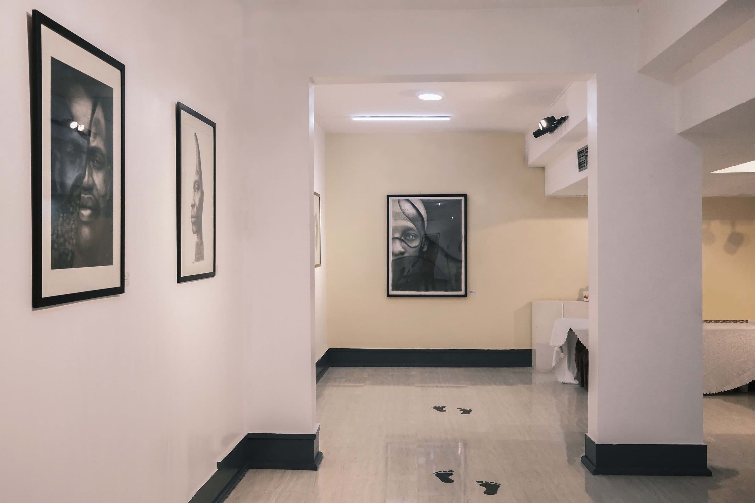 A corridor lined with framed charcoal portraits