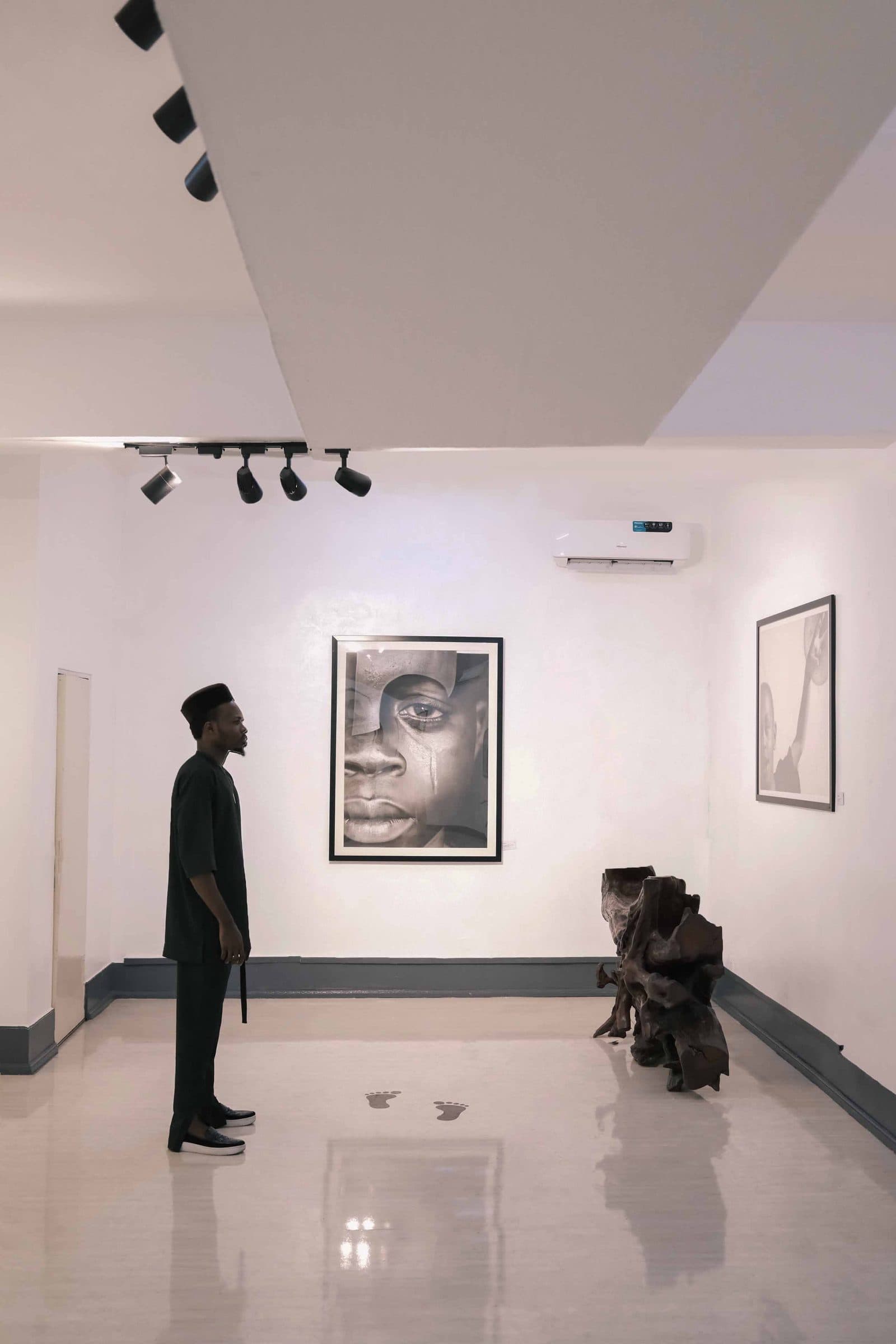 A visitor stands before a large framed portrait in a white room