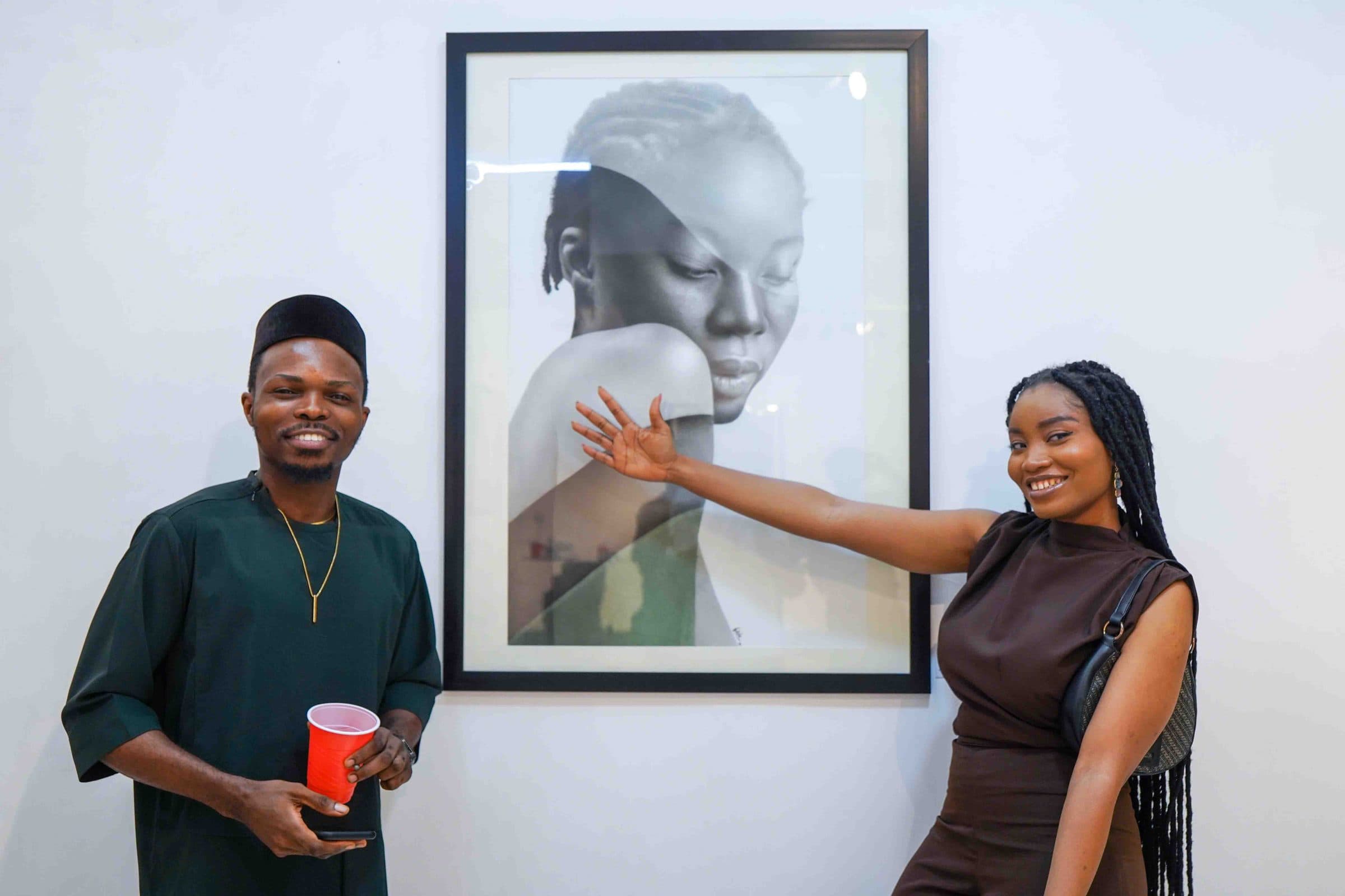 Two guests beside a portrait, one pointing at the work