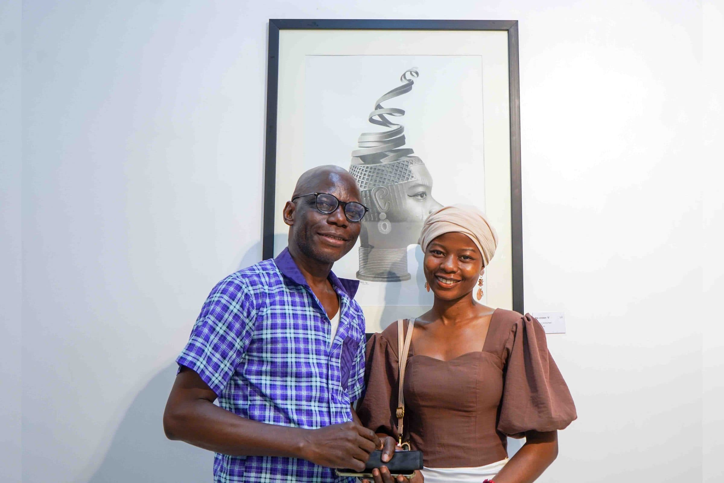 Two guests in front of a portrait with a coiled crown