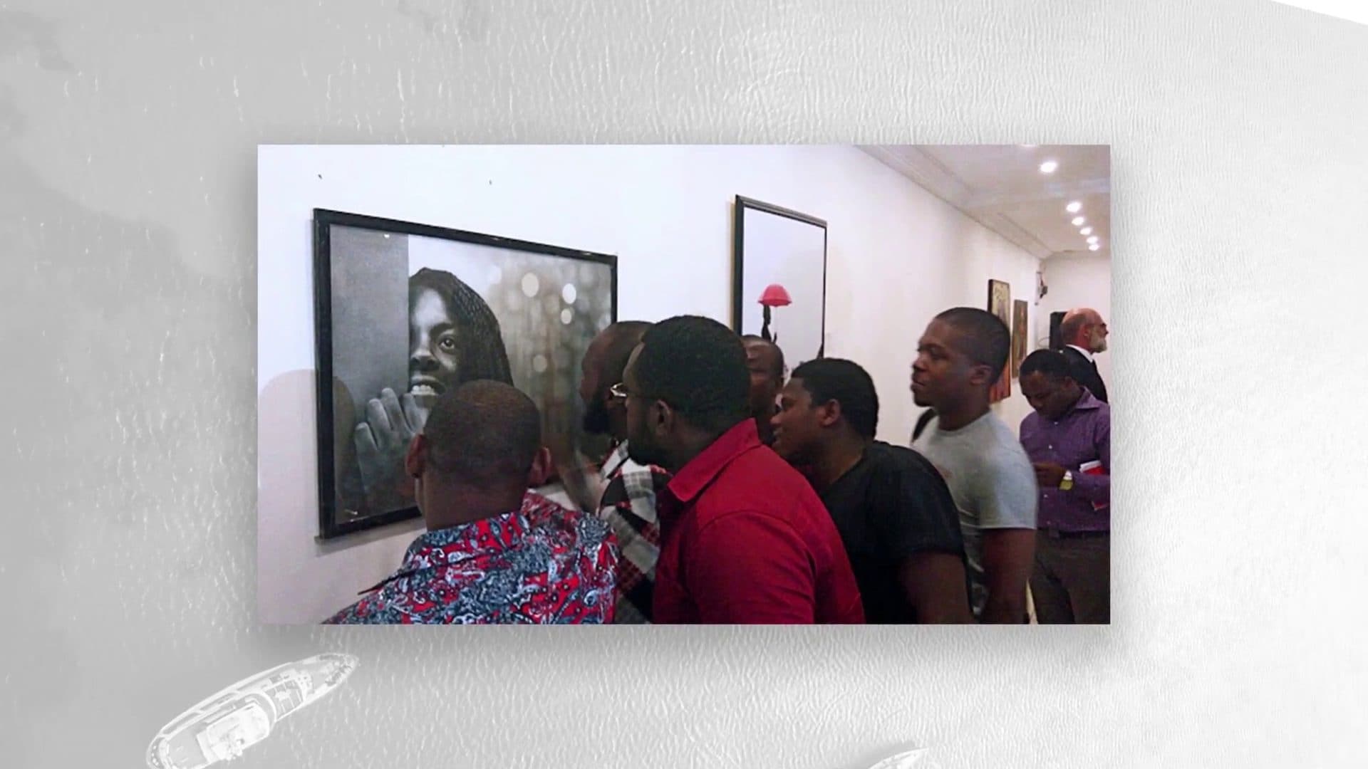 A crowd gathered around a large portrait in a gallery