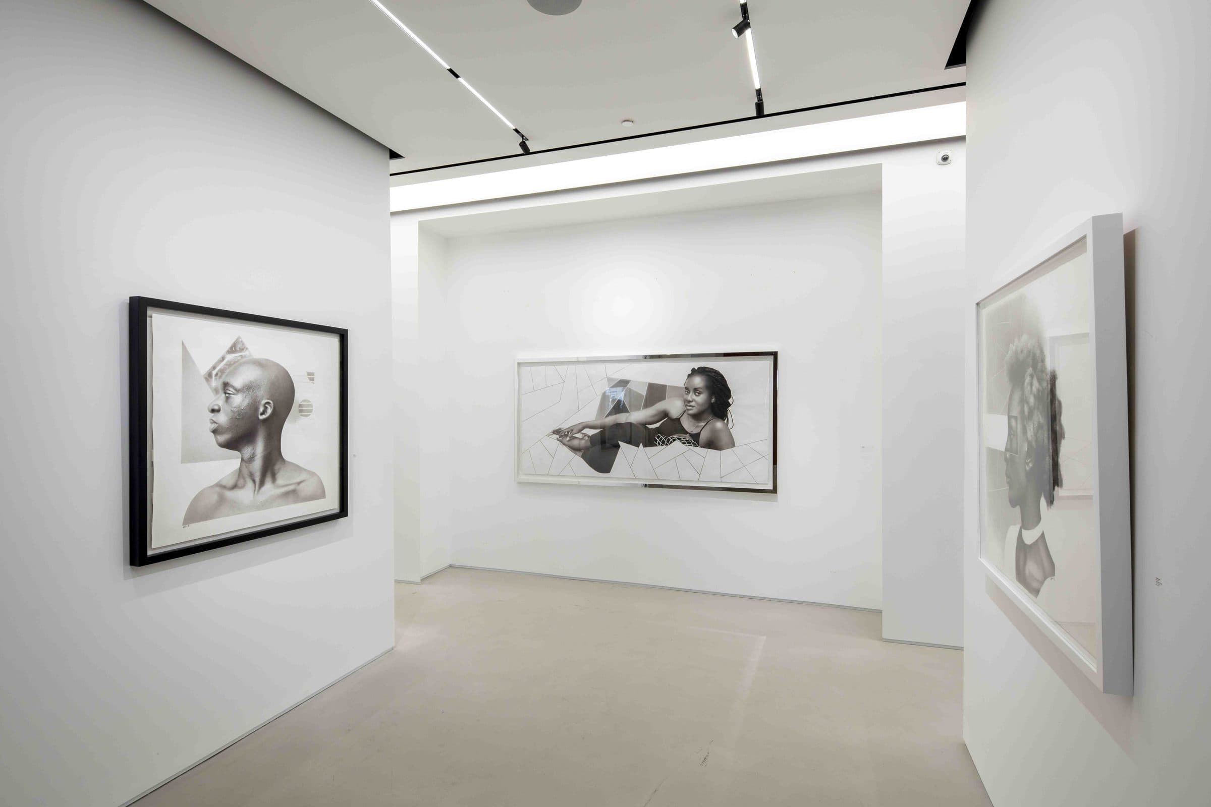 A gallery room hung with large framed charcoal portraits